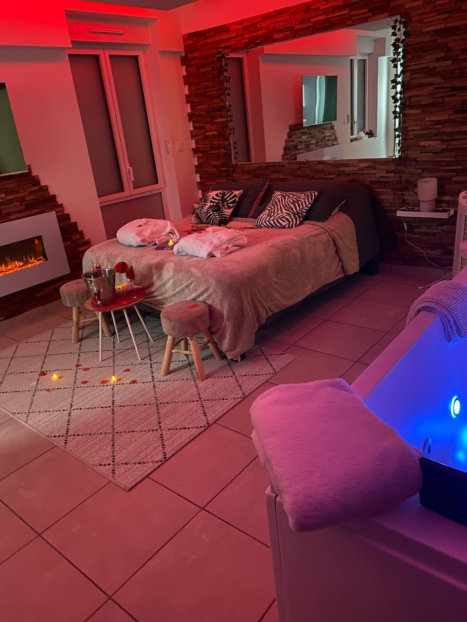 La chambre en éclairage rouge, avec sa table basse et la baignoire balnéo au premier plan