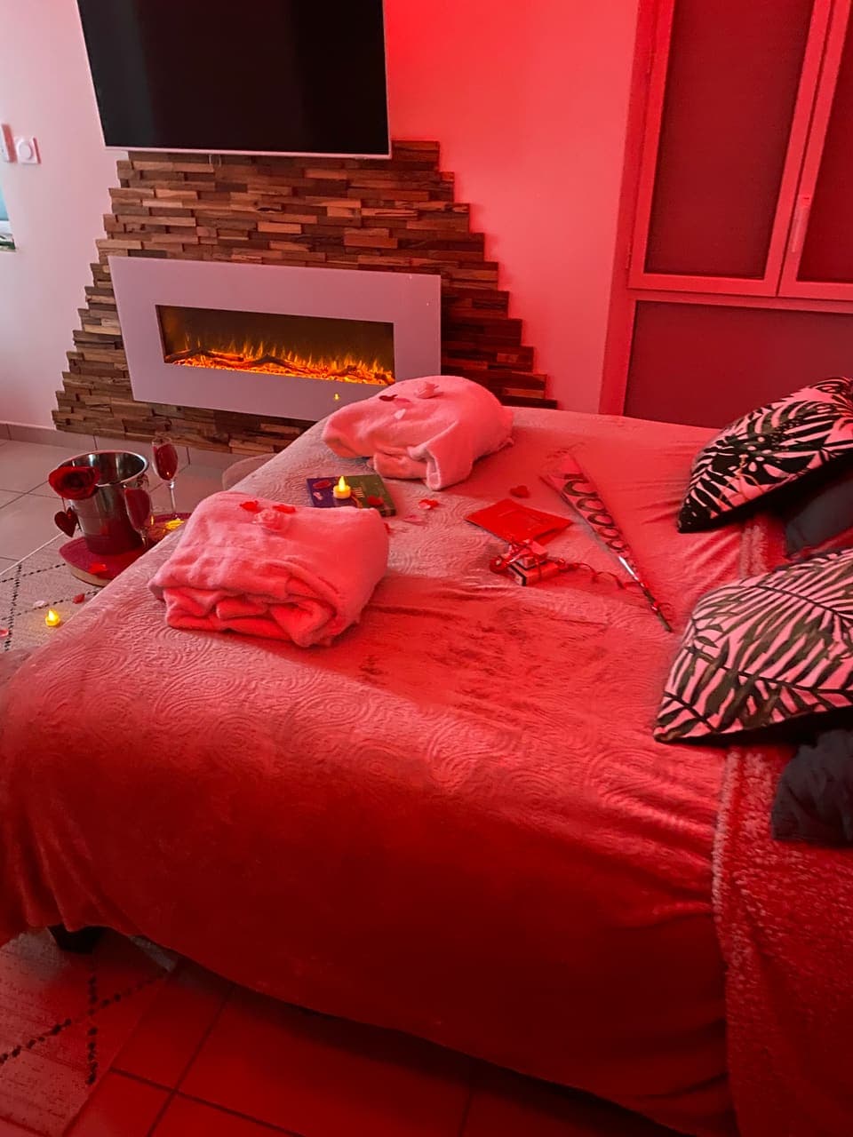 Le lit dressé avec deux peignoirs et le champagne, devant la cheminée